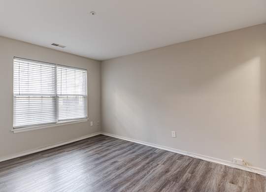 A room with wooden flooring and a window with blinds.
