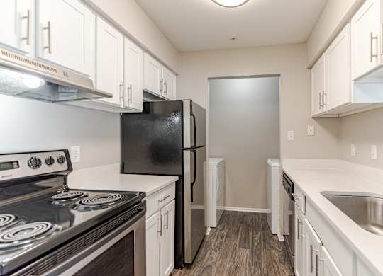 A kitchen with black appliances and white cabinets.