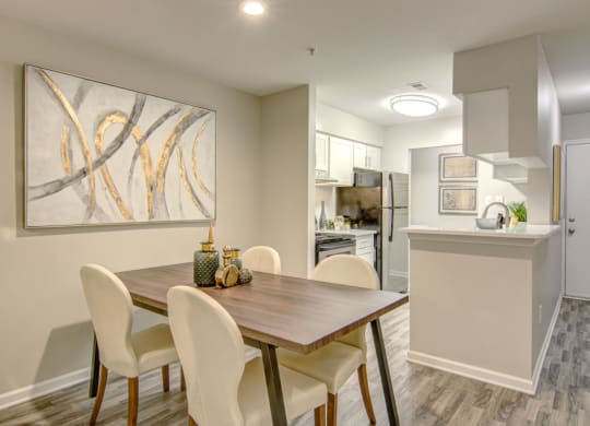 a dining area with a wooden table and white chairs at Hunters Chase Apartments, Virginia