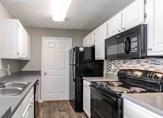 A kitchen with black appliances and white cabinets.