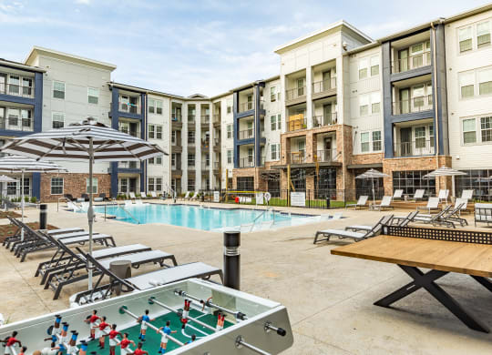 an outdoor pool with tables and chairs and an apartment building at The Louis Apartment Flats, Louisville