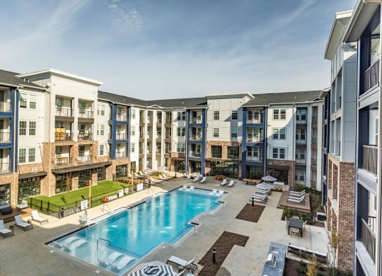 an apartment building with a swimming pool and lounge chairs at The Louis Apartment Flats, Louisville