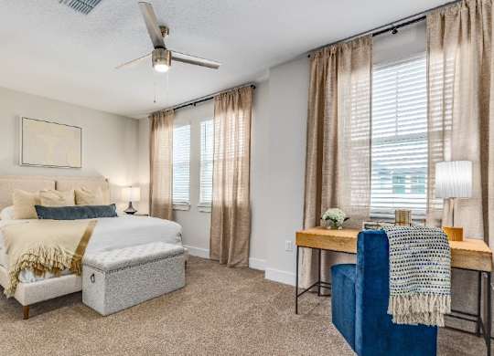 A bedroom with a bed, a chair, and a table.