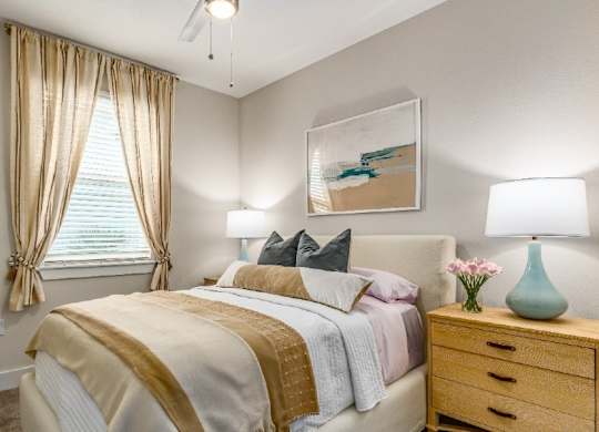 A bedroom with a bed, nightstand, and a painting on the wall.