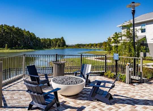 A patio with chairs and a bowl of stones overlooking a lake.