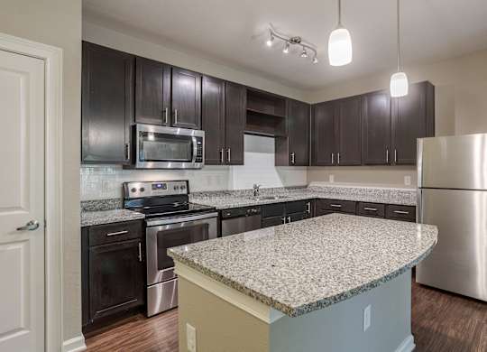 A kitchen with a granite countertop and stainless steel appliances.