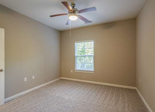 A room with a ceiling fan and a window.