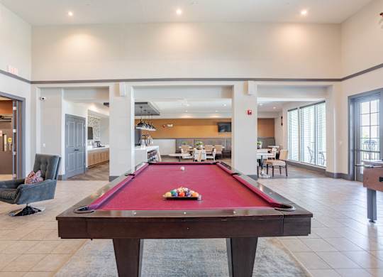 A pool table is in the middle of a room with a couch and chairs.