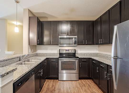 A kitchen with black cabinets and stainless steel appliances.