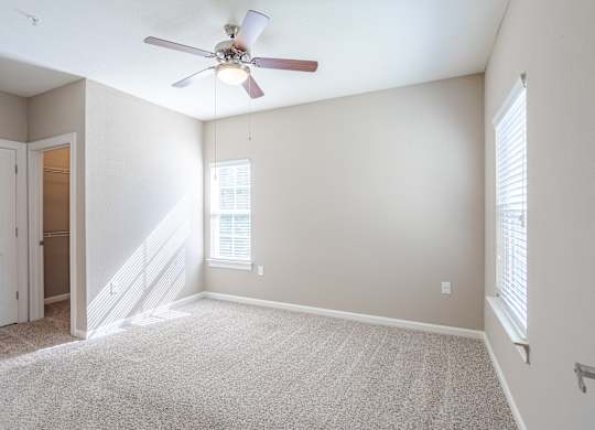 A room with a ceiling fan and carpeted floor.