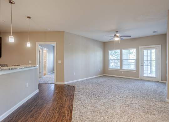 A spacious room with a ceiling fan and a large window.