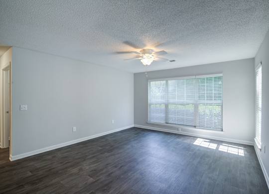 A room with a ceiling fan and a window with blinds.