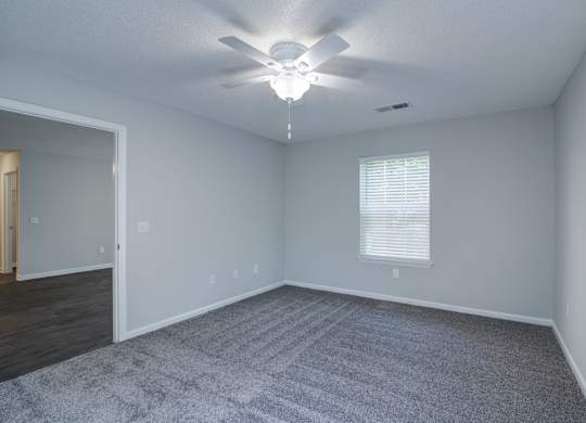 A room with a ceiling fan and a window with blinds.