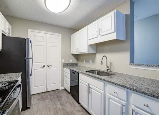 A kitchen with white cabinets and a black refrigerator.