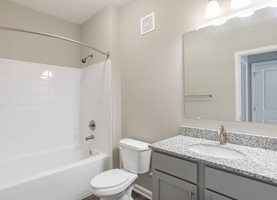A white toilet sits next to a white bathtub in a bathroom.