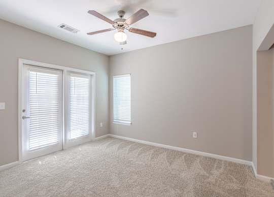 A room with a ceiling fan and two windows with blinds.