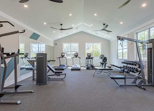 A spacious gym with a variety of equipment including treadmills, elliptical machines, and weight machines.