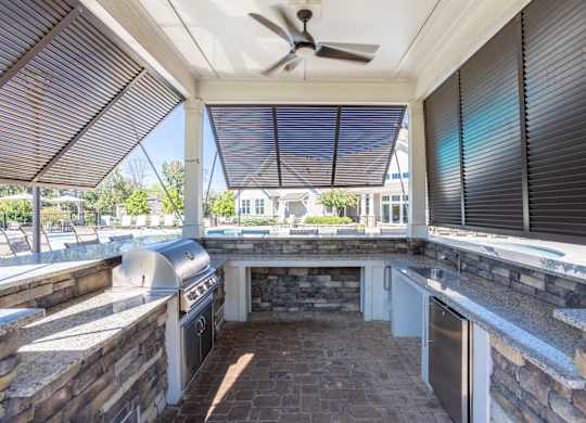 A patio with a grill and a fan.