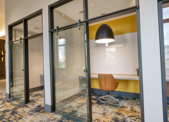 a conference room with a yellow accent wall and glass sliding doors