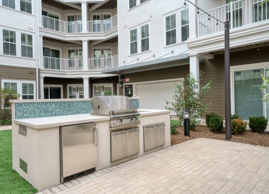 an outdoor kitchen with stainless steel appliances in front of a house