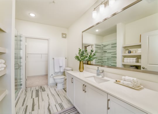 a bathroom with a large mirror and a toilet and a shower