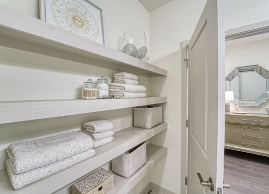 a bathroom with shelves filled with towels and a closet