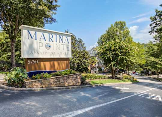 A sign for Marina Pointe Apartment Homes is in front of a street.