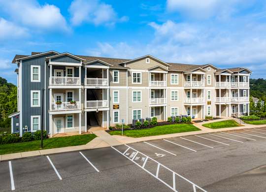 A large apartment complex with a parking lot in front.