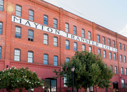 a large brick building with a sign on the side of it at Mayton Transfer Lofts, Petersburg Virginia