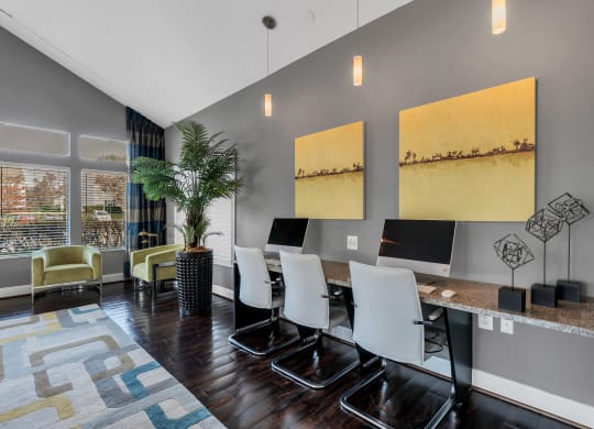 a room with a long desk with four computers on it and two large paintings on the wall at Misty Ridge Apartments, Woodbridge, VA 22191