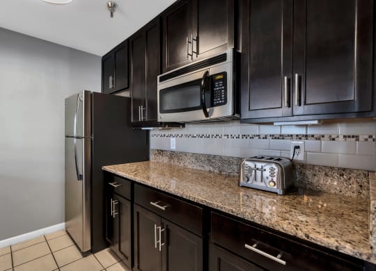 a kitchen with dark cabinets and granite countertops at Misty Ridge Apartments, Woodbridge, VA 22191