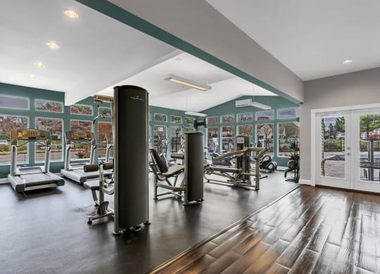 a gym with exercise equipment and a glass door with a view of a parking lot at Misty Ridge Apartments, Woodbridge, VA