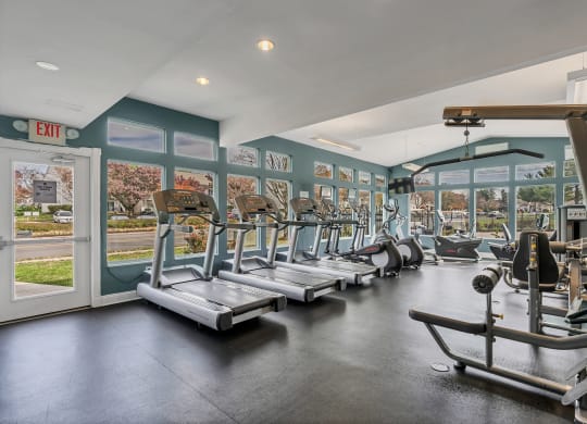 a gym with cardio equipment and windows with a view of the street at Misty Ridge Apartments, Virginia
