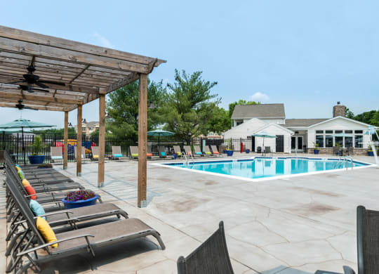 a swimming pool with lounge chairs and umbrellas at Misty Ridge Apartments, Woodbridge Virginia