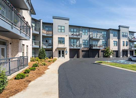 A modern apartment complex with a paved driveway in front.