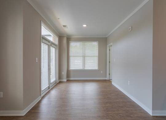 A room with wooden floors and a window with blinds.