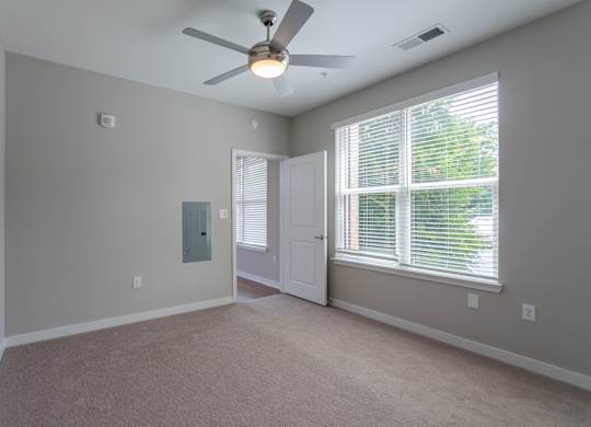 A room with a ceiling fan and a window with blinds.