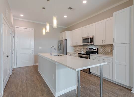 A kitchen with white cabinets and a white island.