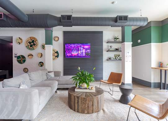 A living room with a white couch, a wooden coffee table, and a flat screen TV mounted on the wall.