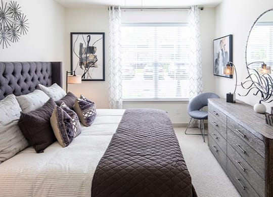 a bedroom with a large bed and a dresser at Canopy at Ginter Park Apartments in Richmond, VA 23227