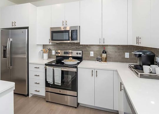 a kitchen with a stove top oven next to a refrigerator at Canopy at Ginter Park Apartments in Richmond, 23227