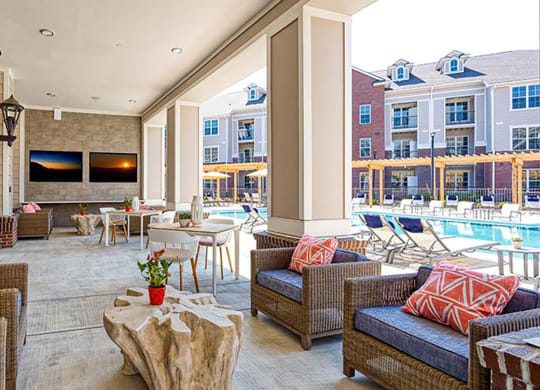 a patio with wicker furniture and a pool in the background at Canopy at Ginter Park Apartments in VA 23227