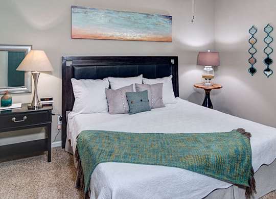 A bedroom with a large bed and a painting on the wall at Austin Chase Apartments, Georgia