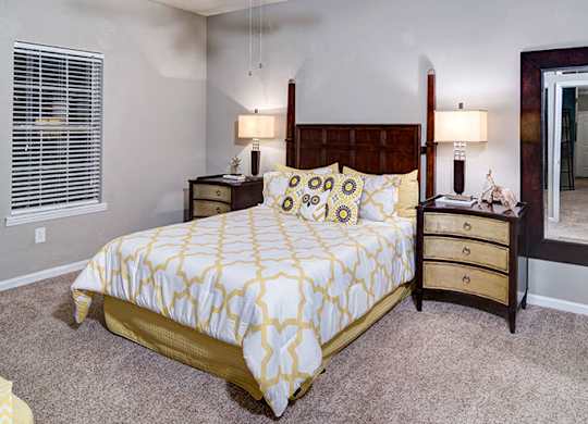 A bedroom with a bed, nightstands, and a dresser at Austin Chase Apartments, Macon