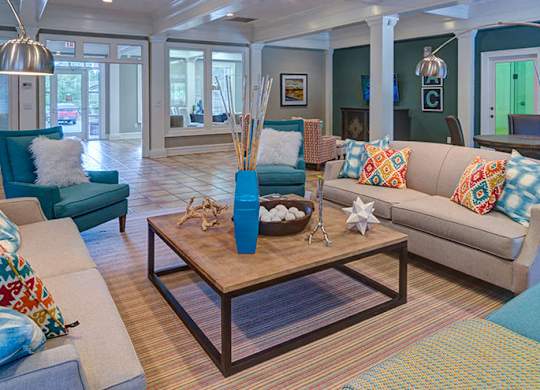 A living room with a sofa, armchair, and coffee table at Austin Chase Apartments, Macon, GA