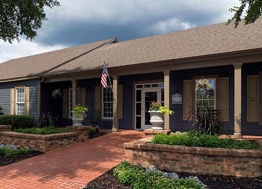 A house with a flag on the porch and a brick pathway leading to the front door at Austin Chase Apartments, Macon, GA 31210