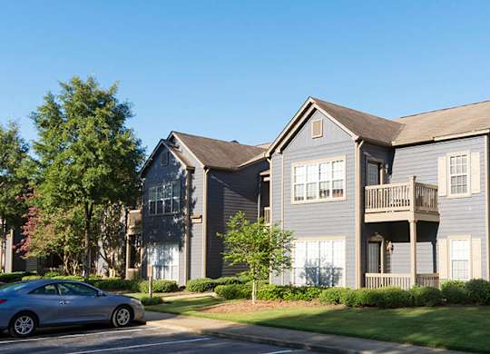 A grey two story apartment building with a car parked in front at Austin Chase Apartments, Georgia