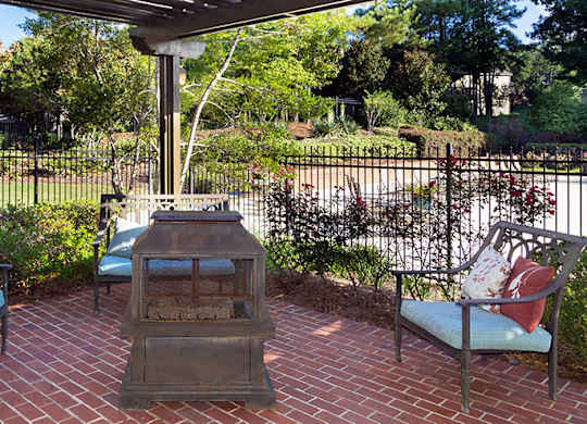 A patio with a fireplace and two chairs at Austin Chase Apartments, Macon, GA