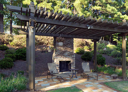 A patio with a fireplace and chairs under a wooden pergola at Austin Chase Apartments, Macon, GA