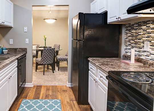 A kitchen with a black refrigerator and a table with chairs in the middle at Austin Chase Apartments, Georgia 31210